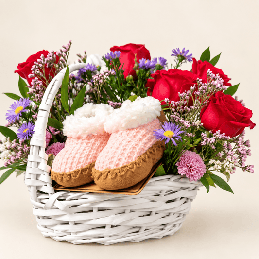 Close-up of The Little Bloom baby flower basket with pink baby booties, hot pink roses, and lavender flowers