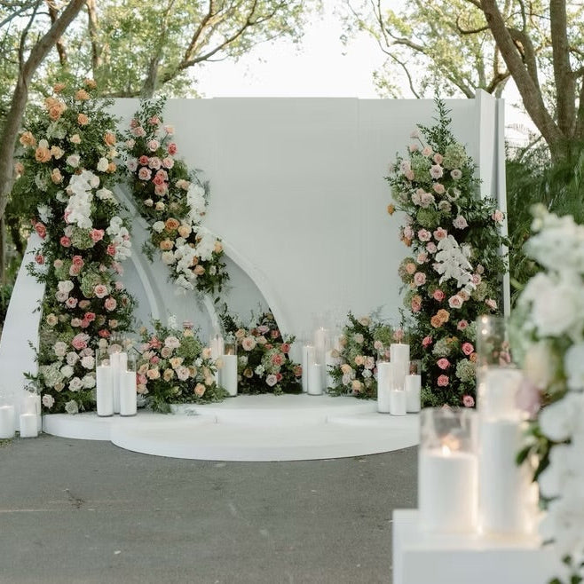 Decorative floral archway with candles at an outdoor wedding venue.