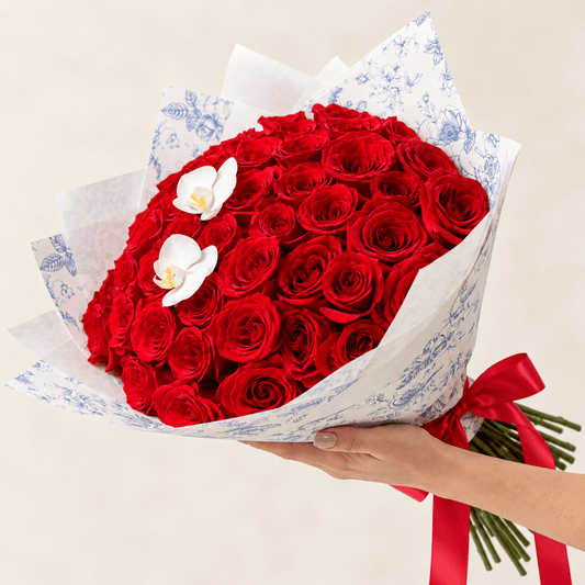 Luxury red rose bouquet with white orchids and blue floral wrapping by AG Floral Studio in Miami