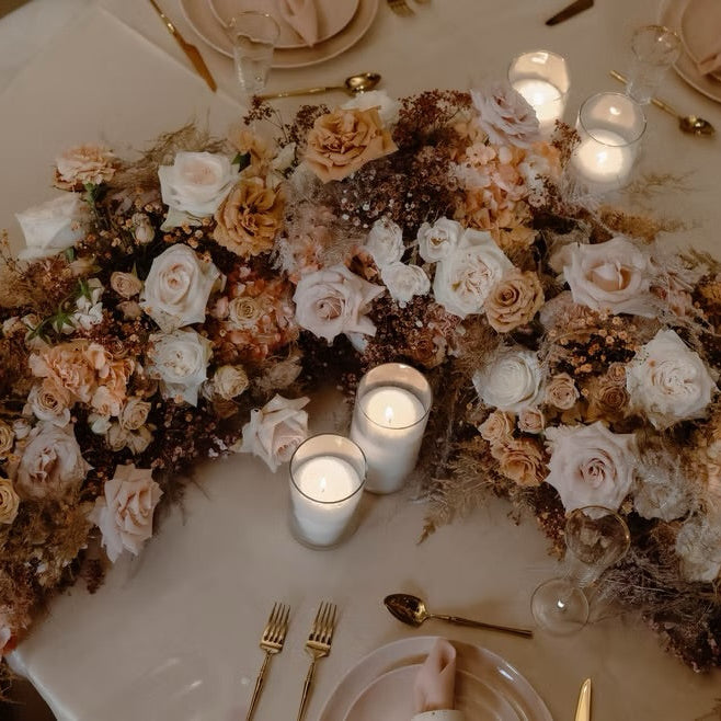 Decorative floral arrangement with candles on a table setting.