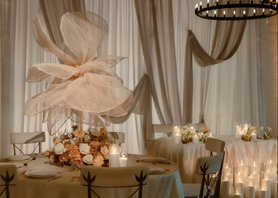Earthy wedding reception with warm-toned florals, flowing fabric details, drapery, and candlelight in Miami