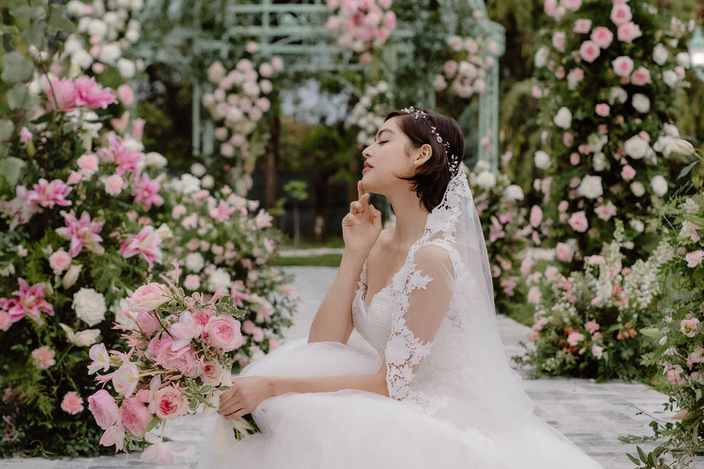 Bride surrounded by pink and white garden flowers with a floral ceremony arch at a Miami wedding