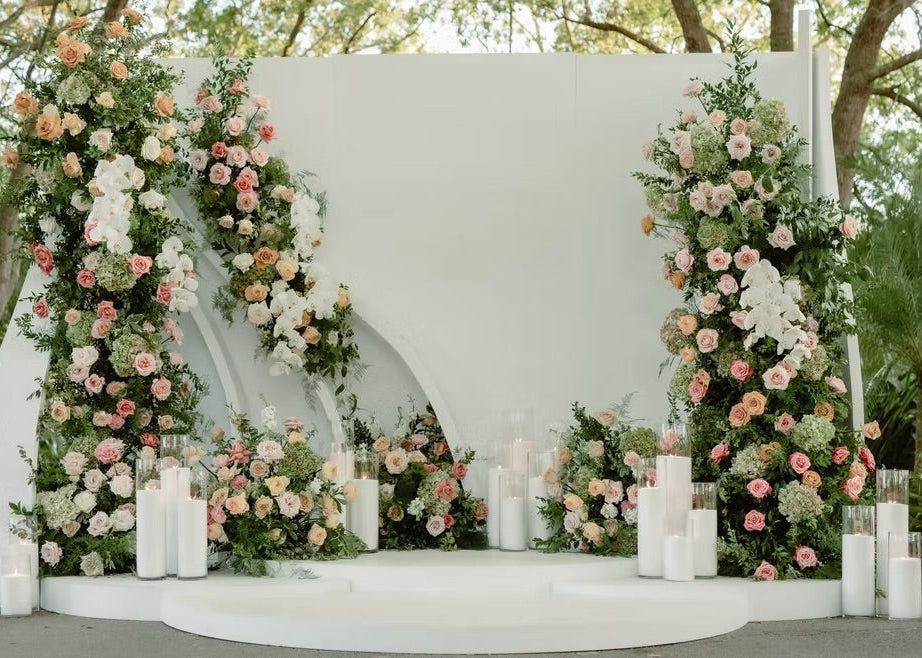 Outdoor Miami wedding ceremony with a floral arch of blush and white flowers, greenery, and candles