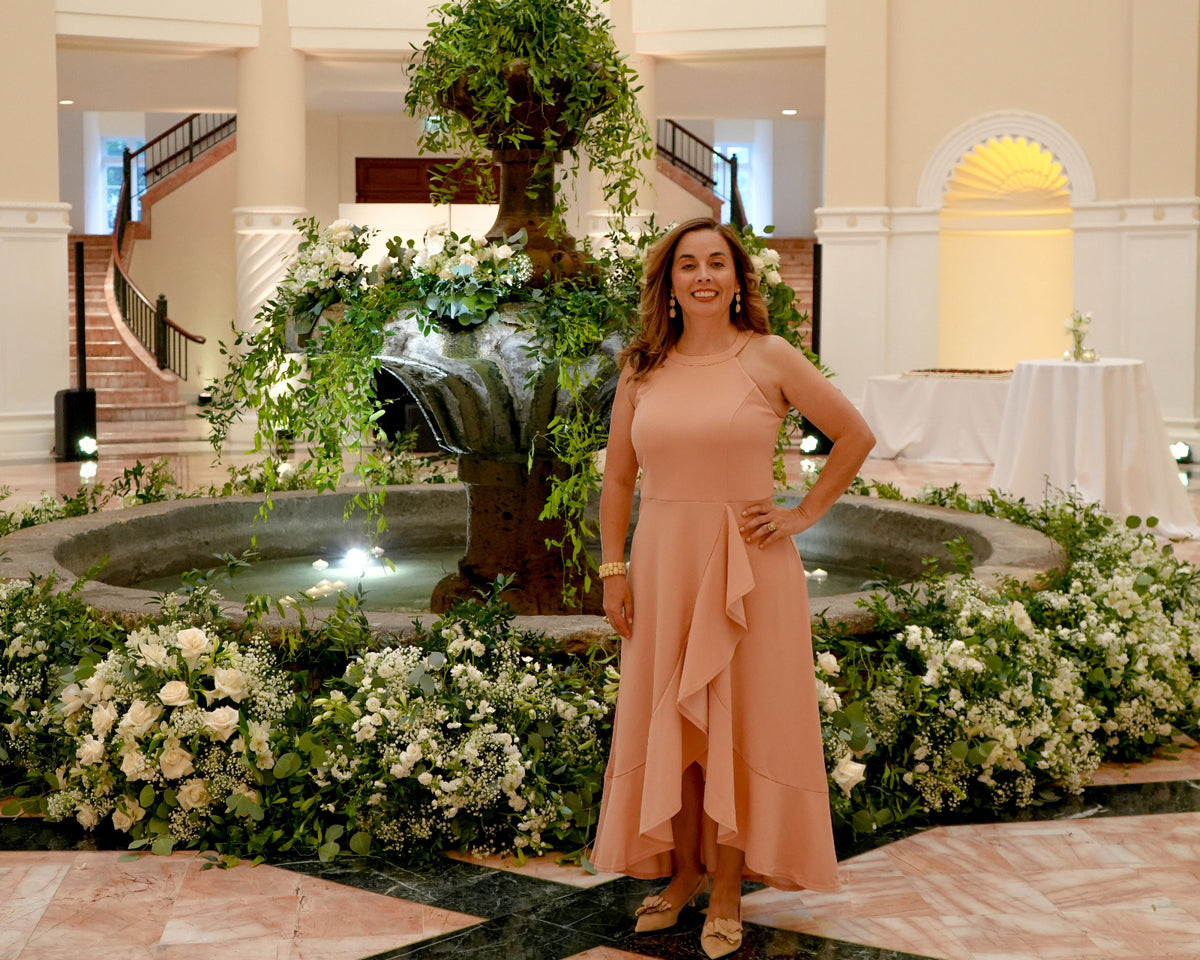 AG Floral Studio floral designer beside a fountain decorated with white flowers and greenery at a Miami wedding venue