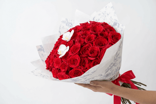 The Red Velvet bouquet with premium red roses and white orchids wrapped in white paper with a red ribbon.