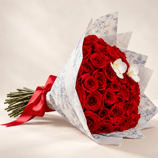 Red rose bouquet with white orchids, blue floral wrapping and red ribbon by AG Floral Studio in Miami