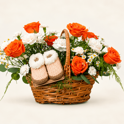 The Little Bloom baby flower basket with orange roses, white flowers, greenery, and baby booties