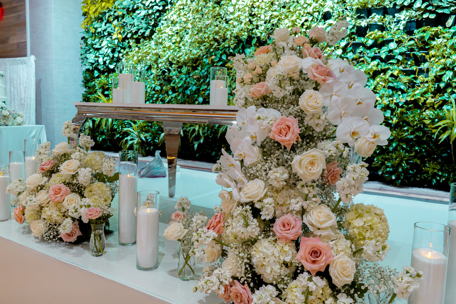 Decorative floral arrangement with candles on a table against a green foliage background