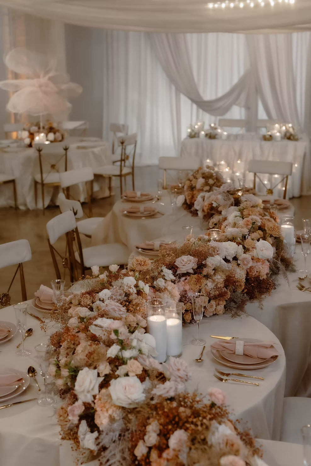 Elegant wedding reception with tables set for dinner, floral arrangements, and candles.