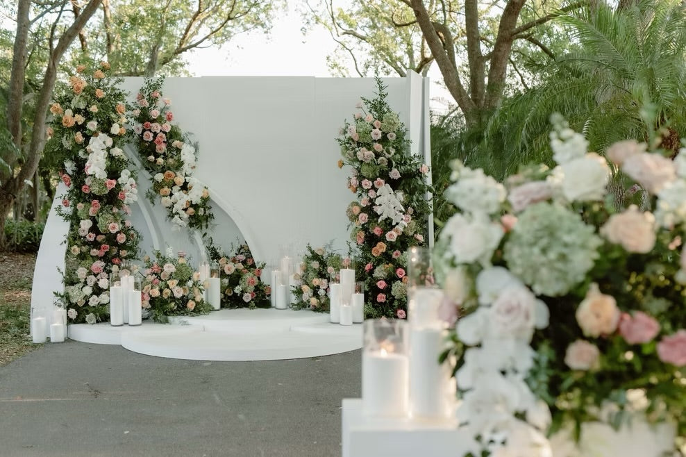 Decorative floral archway with candles at an outdoor wedding venue.