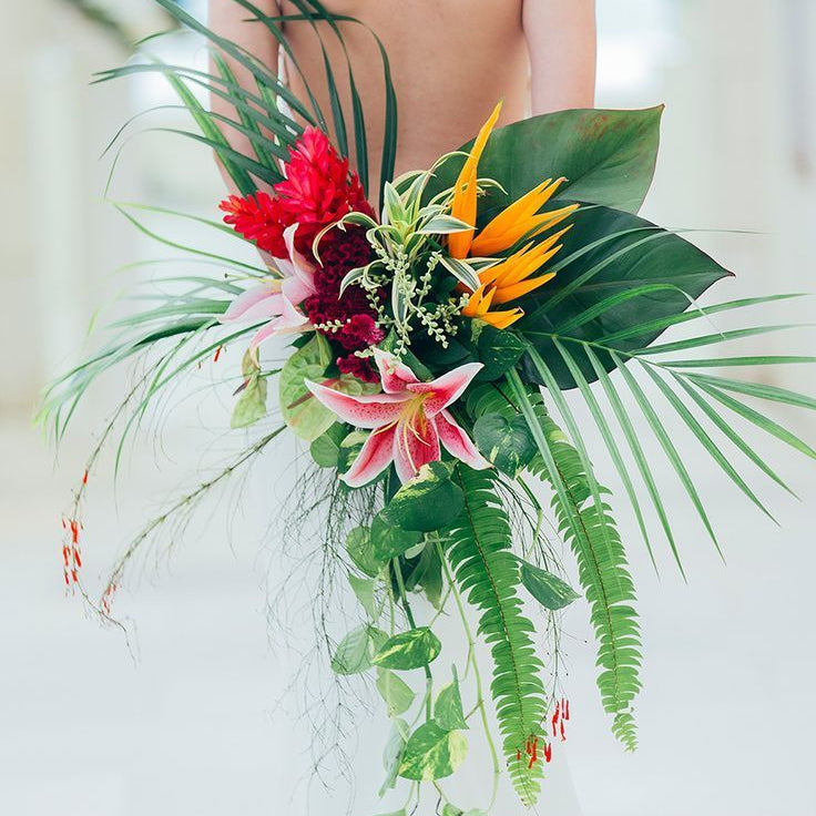 Tropical flower bouquet with red, pink, and yellow flowers with beautiful greenery.